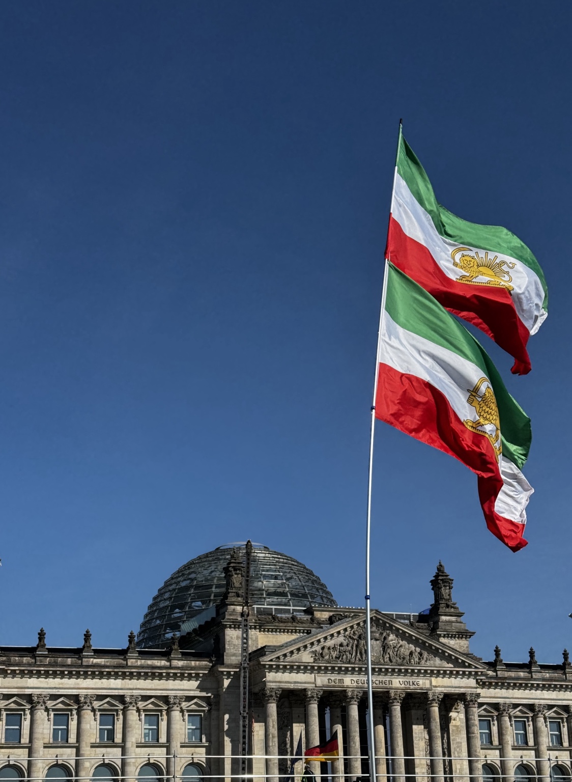 Iranian Lion and Sun flags flying above a gathering in front of the Reichstag in Berlin, Germany.