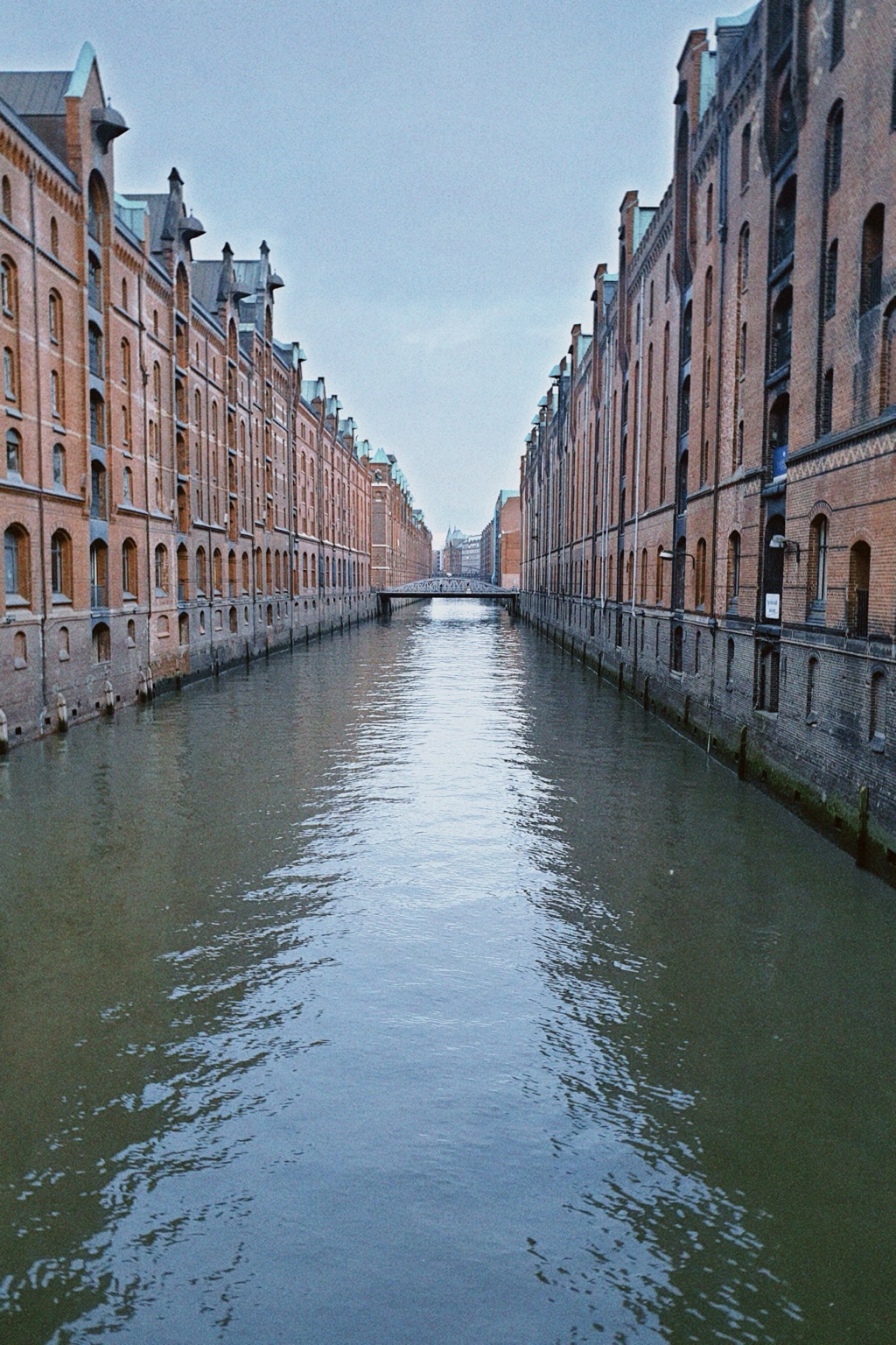Historic red-brick warehouse buildings lining a canal in Hamburg's Speicherstadt.