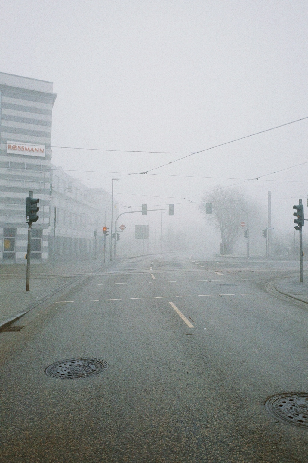 A fog-covered urban intersection in Nordhausen with tram tracks, overhead wires and traffic lights.