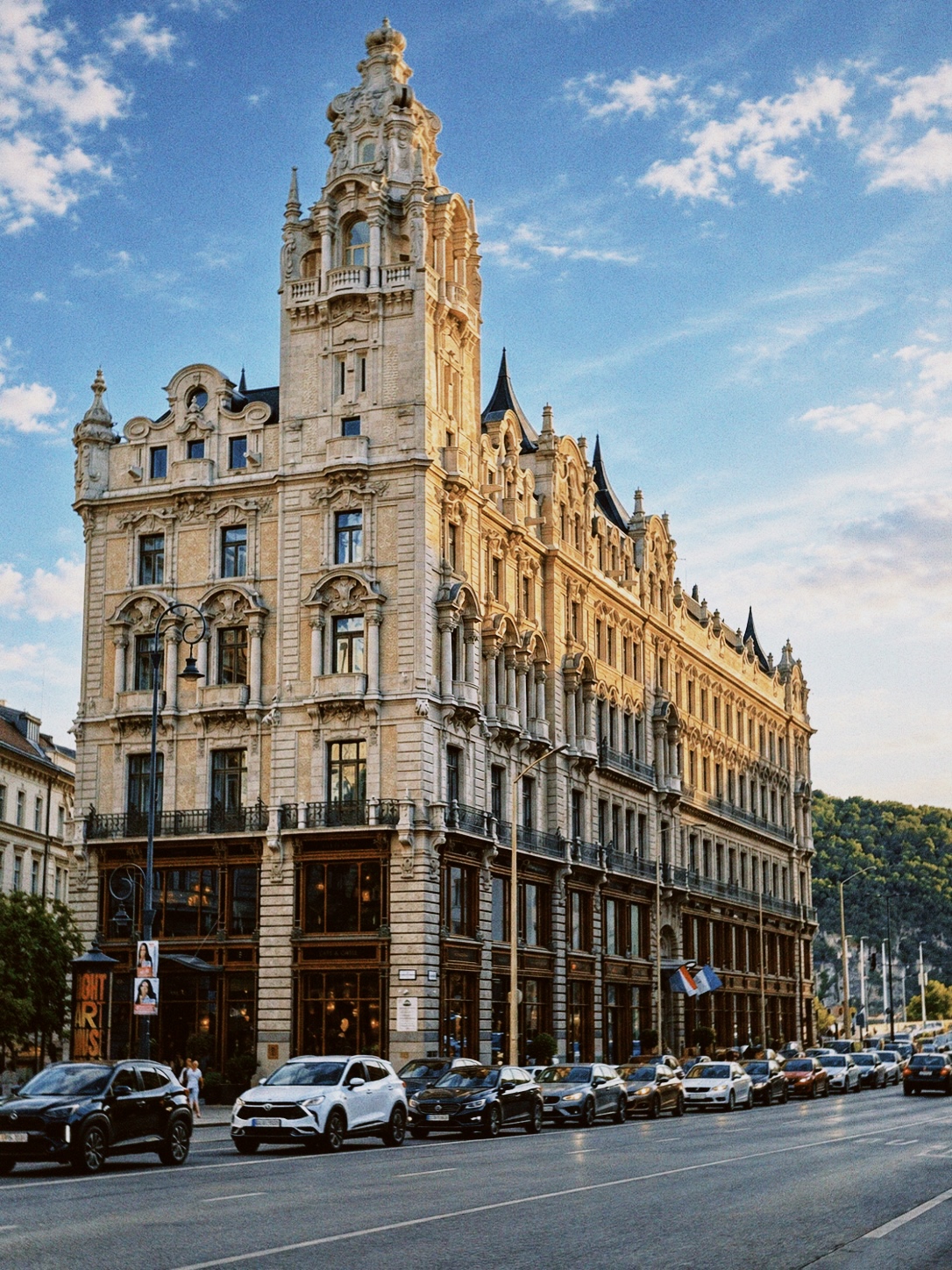 Párisi Udvar in Budapest, Hungary, with its ornate historic facade, tower and street scene under a blue sky.